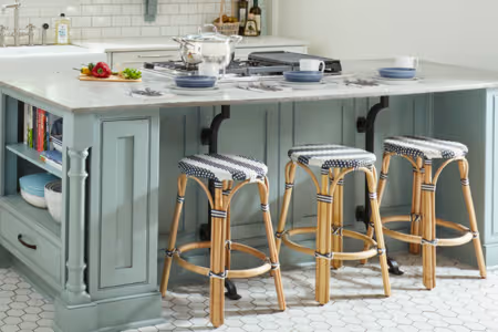 Elegant kitchen island with sage green cabinetry and rattan bar stools